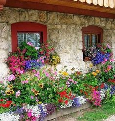 an old stone house with flowers growing out of the windows