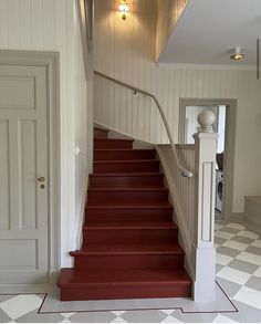 a staircase with red steps leading up to the first floor and another door in the background