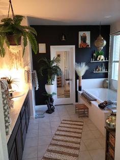 a bathroom with black walls and white tile flooring next to a bathtub filled with plants