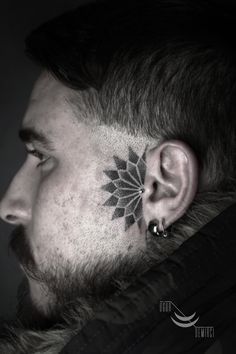 a man with tattoos on his face and ear