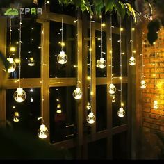 some lights hanging from the side of a brick wall next to a tree and window