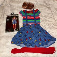 a doll is laying on a bed next to a dress and headband with a book