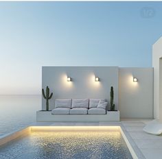 a white couch sitting next to a swimming pool with lights on the side of it