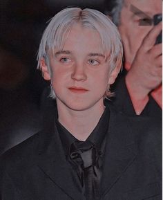 a man with white hair wearing a suit and tie