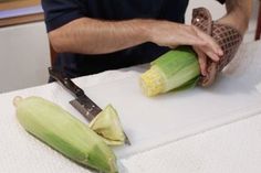 a man cutting corn on the cob with a knife