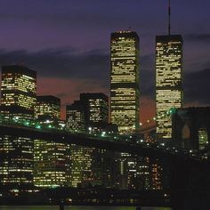 the city skyline is lit up at night, with skyscrapers in the foreground