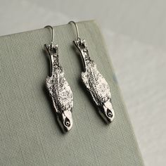 These beautifully detailed and novel earrings feature a stylised silver sardine, hung from a simple silver plated earwire.   Measuring 35mm (just less than 1.5 inches) in length, the fish charm is designed to hang just below the earlobe.  These charms are great quality, but are light and comfortable to wear.   This piece of handmade jewellery comes packaged in a nice recycled gift box with a handmade tag, all ready to give or keep. 🖤 FASTER SHIPPING 🖤 Need this fast? We offer a Faster Shipping option here: https://www.etsy.com/uk/listing/100107311/faster-shipping-priority-post-upgrade 🖤 GIFT MESSAGE & WRAP SERVICE! 🖤 https://www.etsy.com/uk/listing/750160511/gift-wrap-wrapping-personalised-card?ref=listings_manager_table Silver Fish-shaped Earrings With Ear Wire, Handmade Silver Fish-shaped Earrings, Silver Fish-shaped Earrings With Fish Hooks, Nickel-free Silver Fish-shaped Earrings, Sardine Fish, Fish Earrings, Silk Purse, Drop Earrings Silver, Handmade Tags