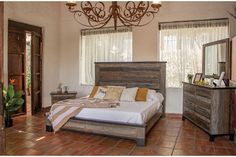 a bed room with a neatly made bed and a dresser under a chandelier