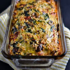 a casserole dish with mushrooms and spinach in it on a yellow towel