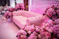 a pink couch sitting next to flowers and candles