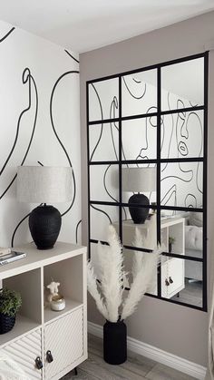 a white room with black and white wallpaper on the walls, two vases and a mirror