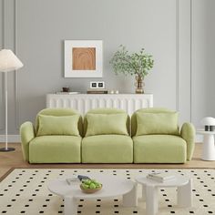 a living room with a green couch and white table in front of the couch is a potted plant