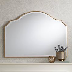 a mirror sitting on top of a mantle next to a vase