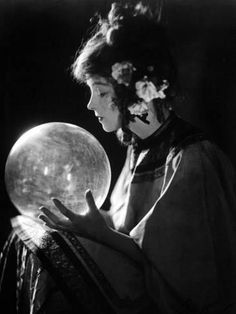 a black and white photo of a woman holding a crystal ball