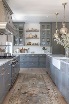 a kitchen filled with lots of gray cabinets and white counter top space next to a rug on the floor