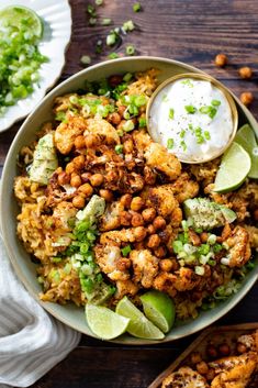 a bowl filled with food and garnished with cilantro, lime wedges and sour cream