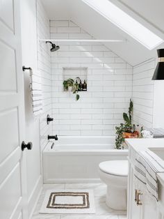 a white bathroom with black and gold accessories on the wall, toilet and bathtub