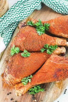 two chicken legs on a cutting board with parsley sprigs and seasoning