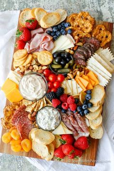 a bunch of different types of cheeses and crackers on a plate with fruit