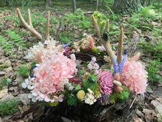 an arrangement of flowers and antlers in the woods