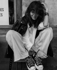 a black and white photo of a woman sitting on a chair with her head in her hands