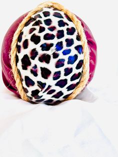 an animal print ball with rope around it on a white sheeted surface in the foreground