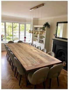 a large wooden table sitting in the middle of a living room next to a fire place