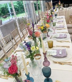 a long table is set with flowers and place settings for the guests to sit down