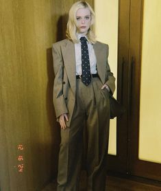 a doll dressed in a suit and tie standing next to a wooden paneled wall