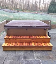 a hot tub sitting on top of a stone patio next to a wooden bench with benches underneath it