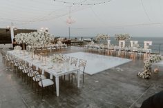 an outdoor wedding set up with white flowers and greenery on the dancefloor