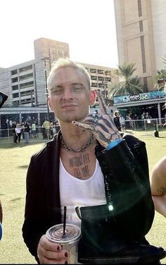 a man with tattoos on his arm holding up a drink in front of two other people