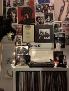 a record player sitting on top of a table next to a wall covered in pictures