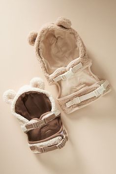 two pairs of baby shoes sitting next to each other on a white surface and one has a brown teddy bear inside