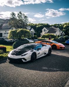 two sports cars parked next to each other on the street in front of some houses