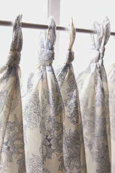 three bags hanging from a window with blue and white designs on them in front of a curtain