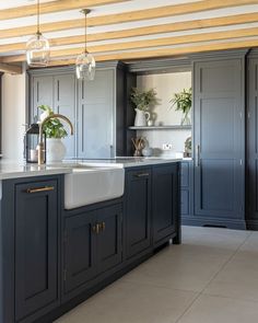 a kitchen with blue cabinets and white counter tops, an island style sink and hanging lights