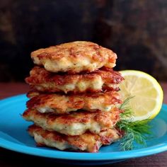 a stack of crab cakes on a blue plate with lemon wedges and whipped cream