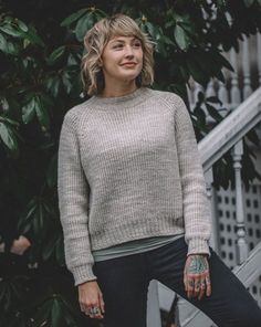 a woman standing in front of a tree with her hands on her hips and looking off to the side