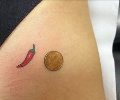 a penny sitting next to a red chili pepper on the back of a woman's shoulder