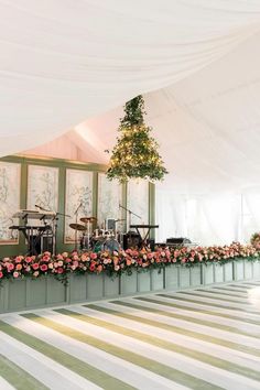 a large white tent with lots of flowers on the floor and music equipment in it