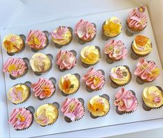 cupcakes decorated with pink and yellow icing are displayed on a white box