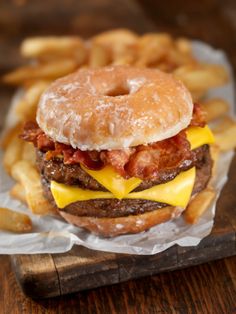 a bacon cheeseburger and french fries on a cutting board