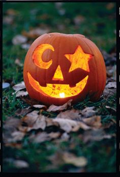 a carved pumpkin sitting on the ground with its eyes open and glowing in the dark