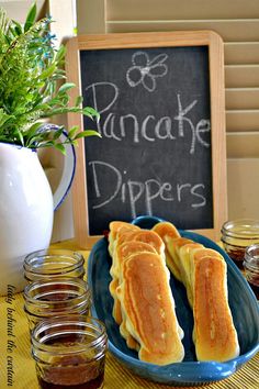 some food is on a blue plate near jars and a chalkboard with the words pancake dippers