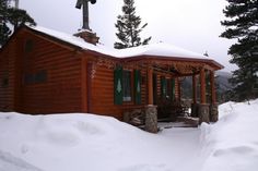 a log cabin covered in snow with a cross on top