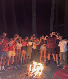 a group of people standing around a campfire