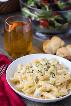 a white bowl filled with macaroni and cheese on top of a wooden table