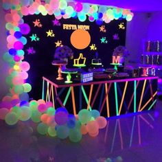 a party with neon lights and balloons on the walls is ready for guests to eat