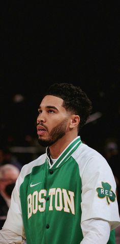 boston basketball player in green and white jacket looking to the side with his hand on his hip